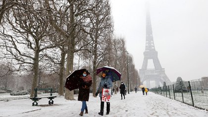 La gente camina con paraguas en el parque Champ de Mars el 16 de enero de 2021 con la Torre Eiffel de fondo (Foto de Ludovic MARIN / AFP)